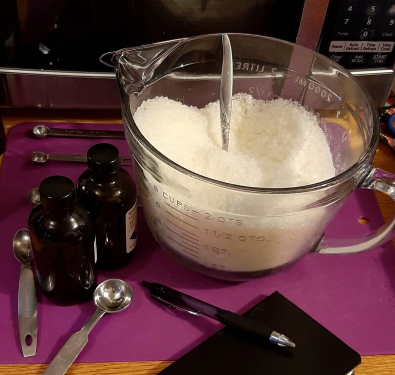 A clear glass measuring bowl filled with white bath salts.