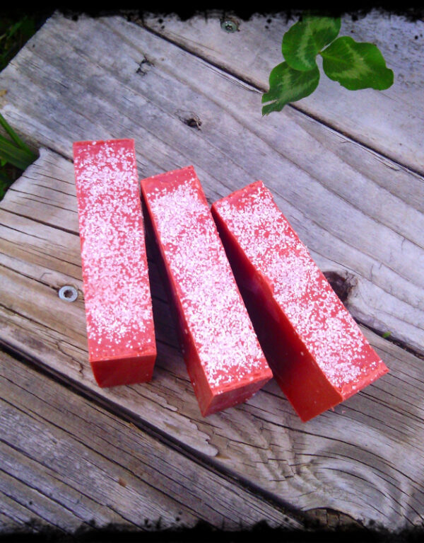 Three bars of deep red soap, with white sea salt sprinkled on top.