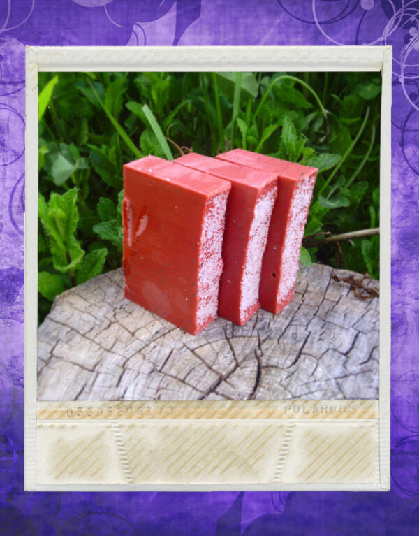 Three bars of deep red soap, with white sea salt sprinkled on top.