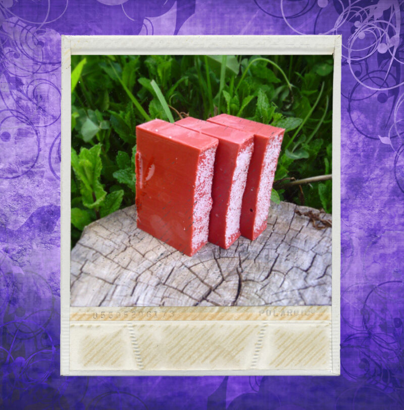 Three bars of deep red soap, with white sea salt sprinkled on top.