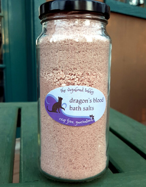 A clear glass jar filled with reddish-brown bath salts.