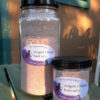 Two clear glass jars filled with reddish-brown bath salts.