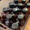 Several amber glass bottles sit in a metal mesh box, just wide enough to hold three bottles across.