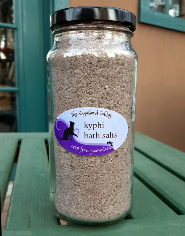 A tall, clear glass jar filled with brown bath salts.