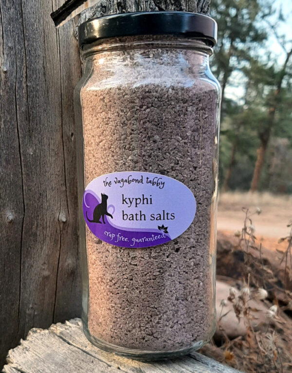 A tall, clear glass jar filled with brown bath salts.