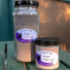 Two clear glass jars, each filled with brown bath salts; one is much taller than the other.