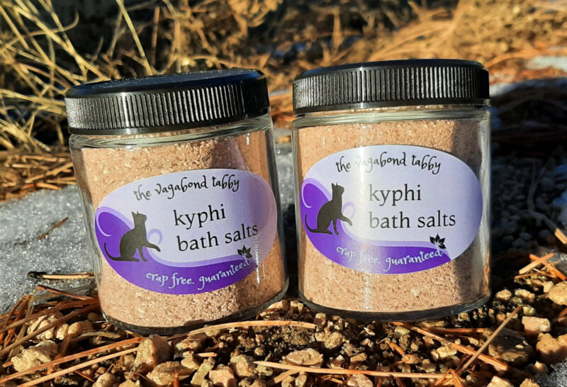 Two clear glass jars, each filled with brown bath salts.