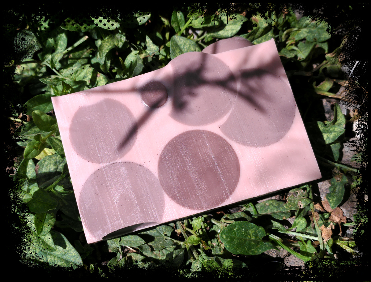 A bar of soap, medium brown with darker brown spheres embedded within.