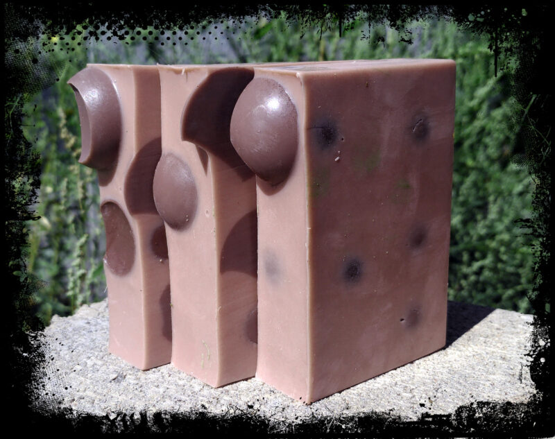 Three bars of soap, medium brown with darker brown spheres embedded within.