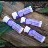 Four white lip balm tubes; the purple labels each name a different color.
