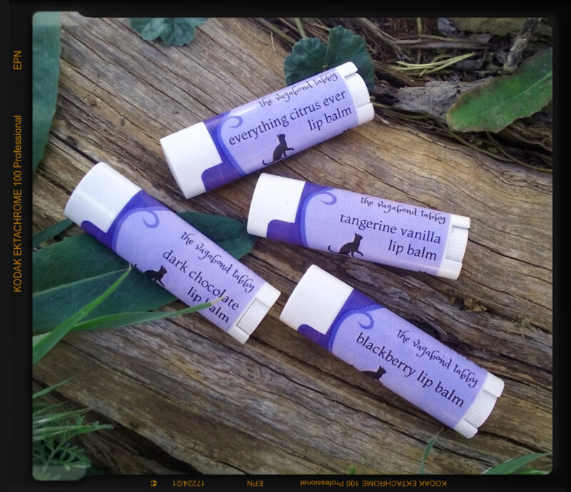 Four white lip balm tubes; the purple labels each name a different color.