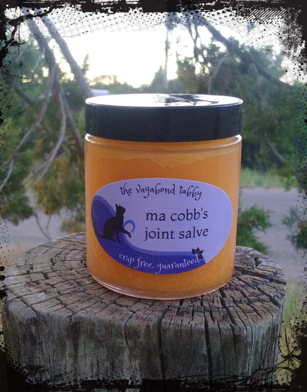 A clear glass jar of orange-tinted salve.