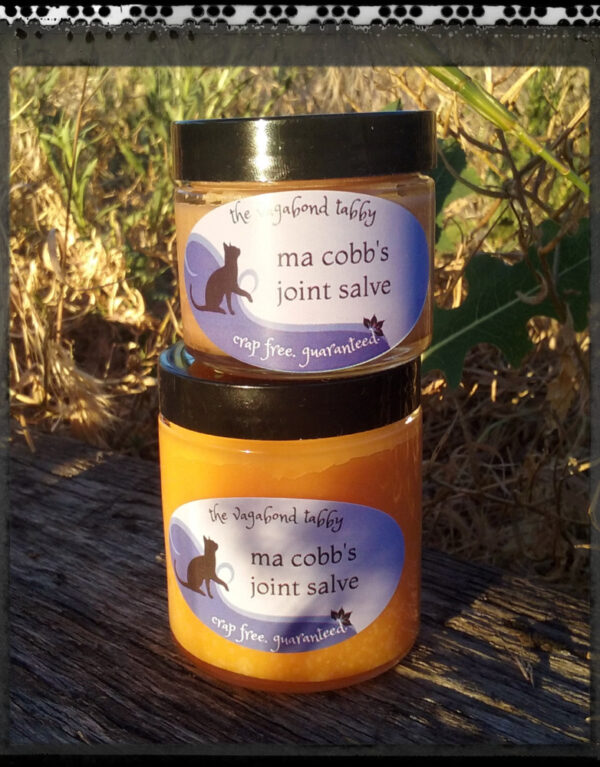 Two clear glass jars of orange-tinted salve; one is larger than the other.