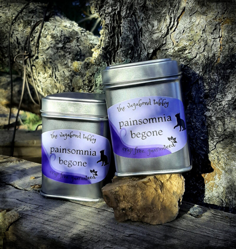 Two metal tea tins; the labels say painsomnia begone.