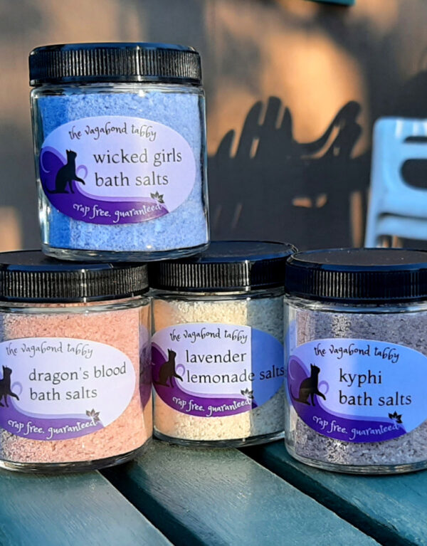 Four glass jars of bath salts, each a different color.