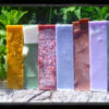 A stack of soap in various colors -- yellow, green, red, pale blue, brown, and purple.