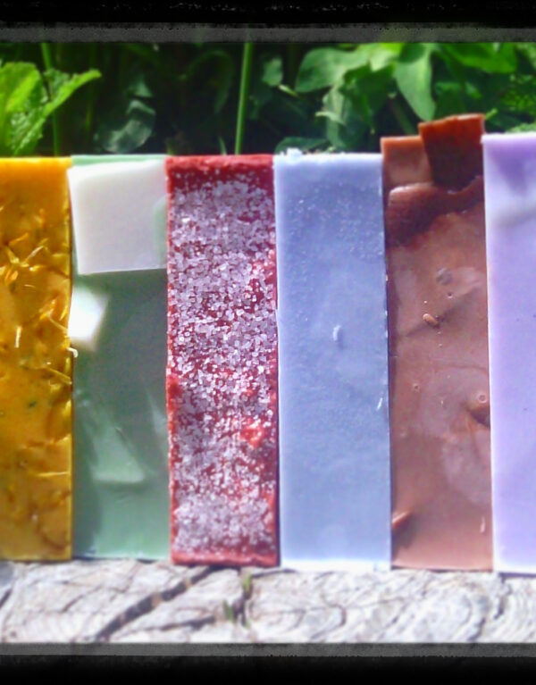 A stack of soap in various colors -- yellow, green, red, pale blue, brown, and purple.