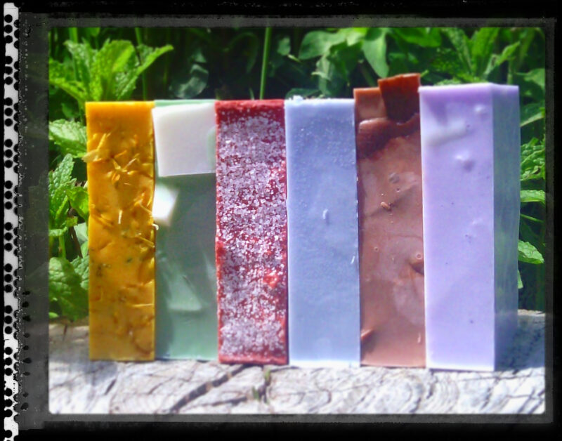 A stack of soap in various colors -- yellow, green, red, pale blue, brown, and purple.