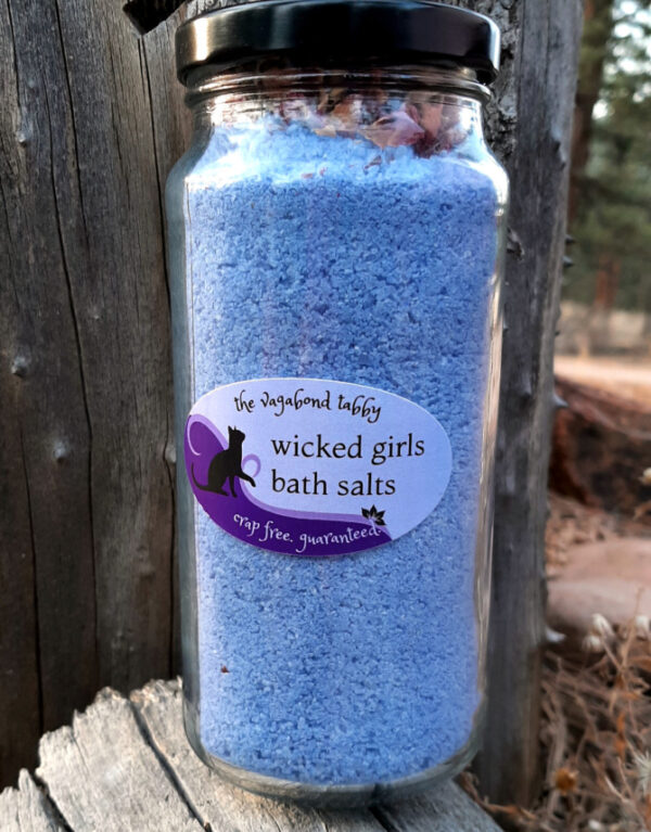 A tall glass jar filled with blue bath salts.