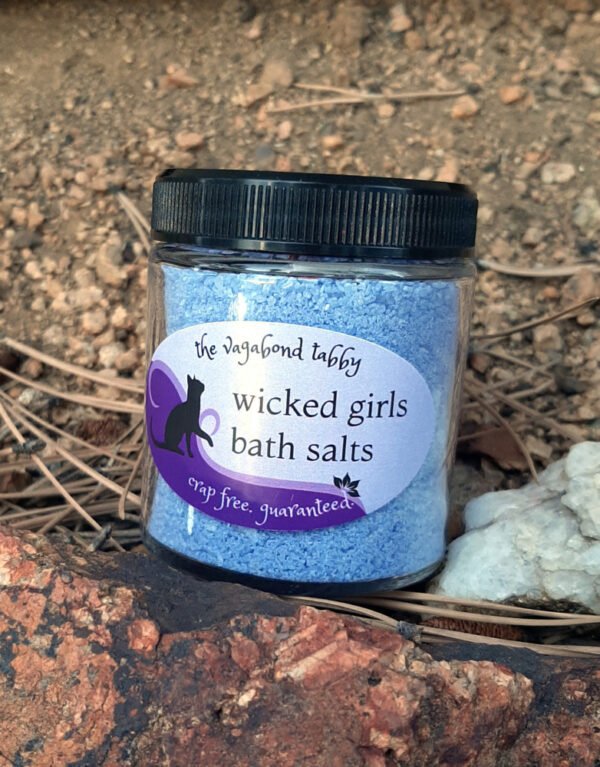 A glass jar filled with blue bath salts.