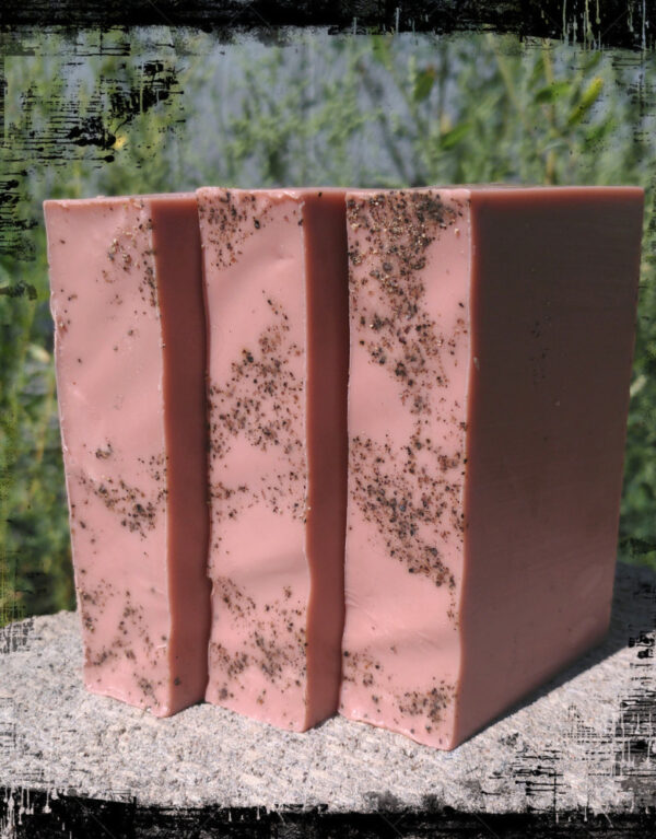 Three bars of medium brown soap sprinkled with black pepper.