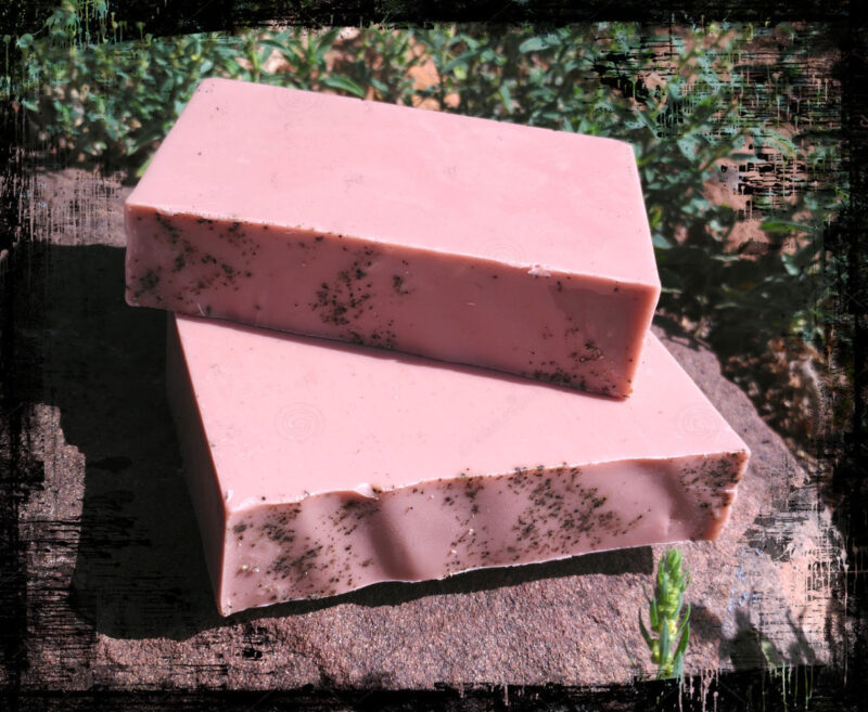 Two bars of medium brown soap sprinkled with black pepper.