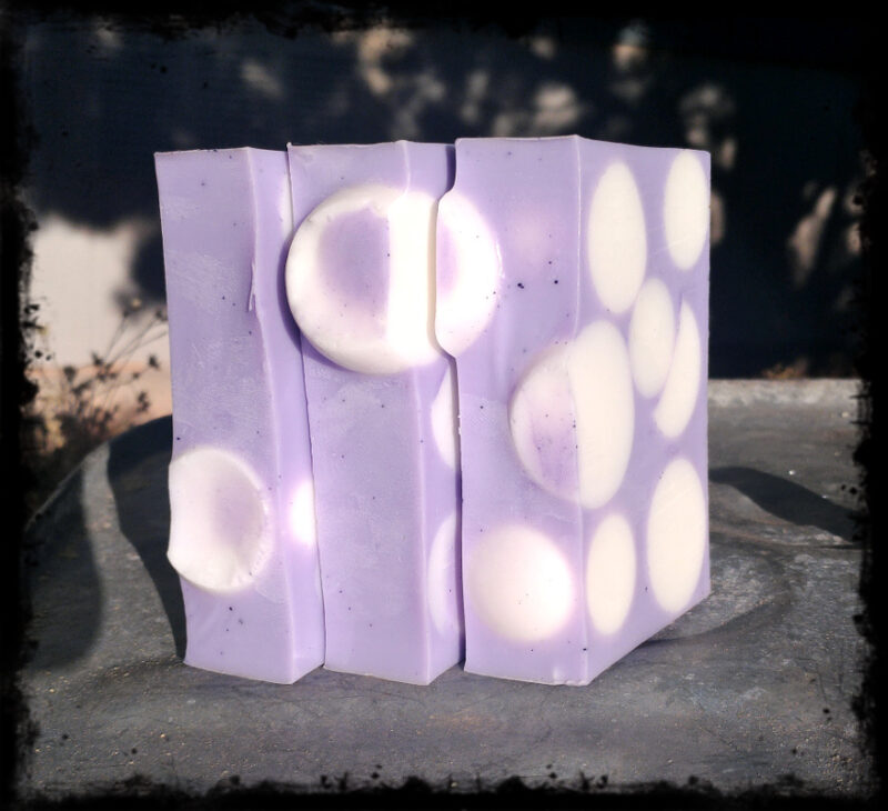 Three bars of soap, purple with white spheres.