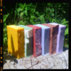 A stack of soap in various colors -- yellow, green, red, pale blue, brown, and purple.