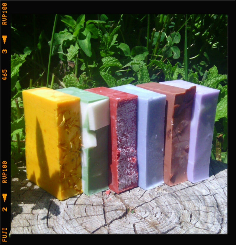 A stack of soap in various colors -- yellow, green, red, pale blue, brown, and purple.