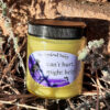 A clear glass jar of pale yellow salve.