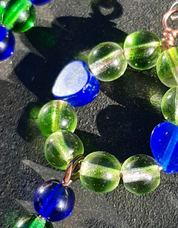 Simple hoops of beads, lime green glass with blue hearts in between; each earring also dangles a strand of round beads, blue green blue, ending in a copper spiral.