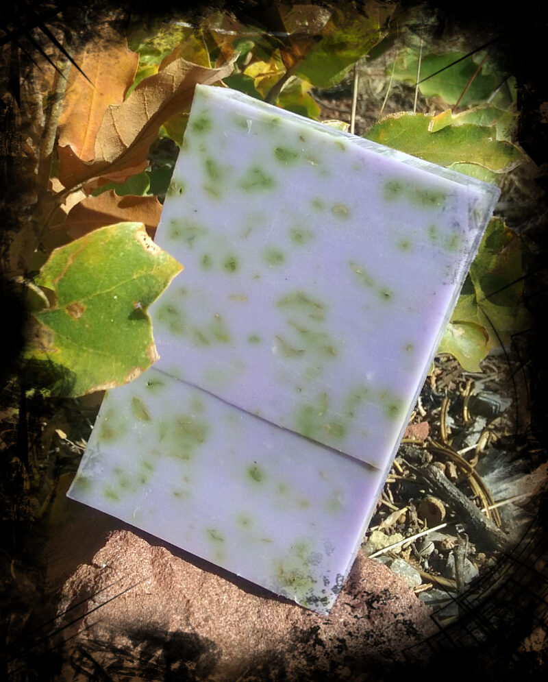 A single bar of soap, purple speckled with green herbs.