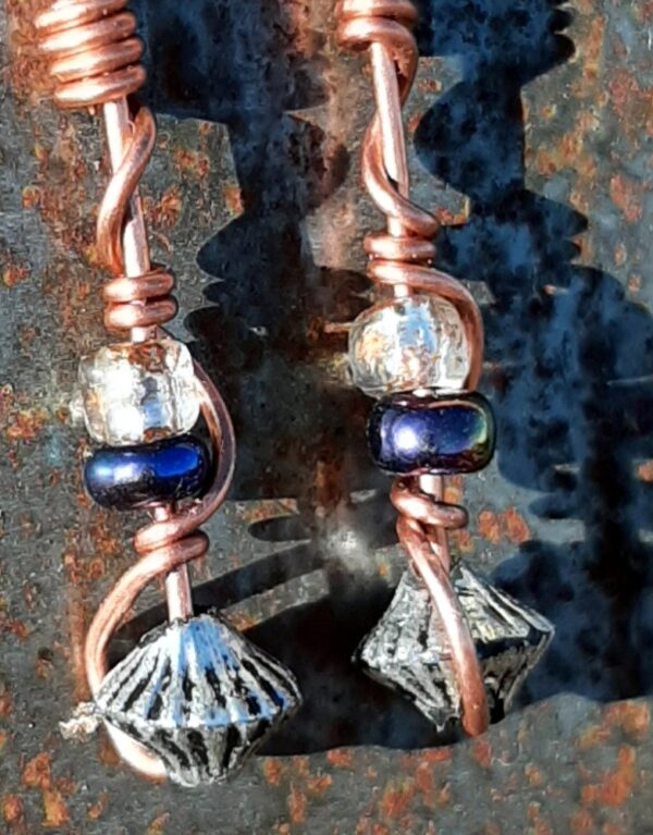 Each earring has a bicone silver-colored bead with an iridescent purple and a clear yellow glass bead above, all strung on copper wire that curves back up around each bead, then twists around itself.