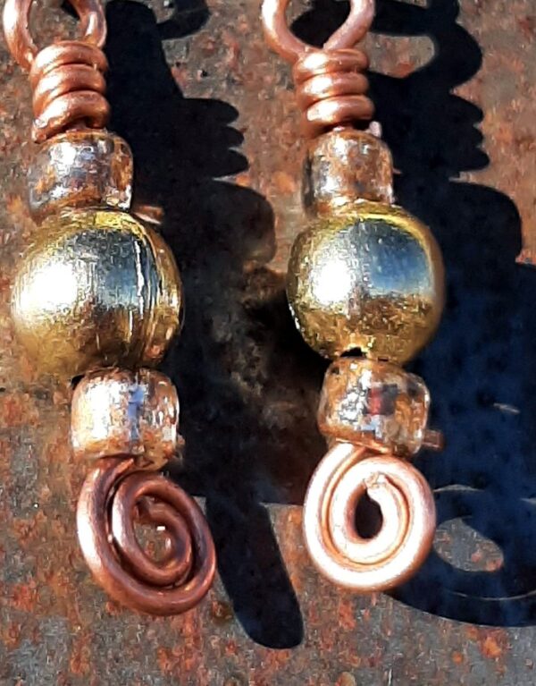 Each earring has a round brass bead with a sparkly orange-brown bead to either side, all strung on copper wire that ends at the bottom in a neat spiral.