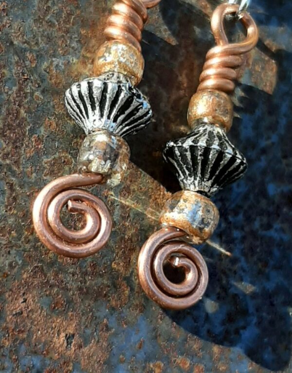 Each earring has a biconic silver-colored bead between two sparkly brown-orange beads, all strung on copper wire that ends at the bottom in a neat spiral.