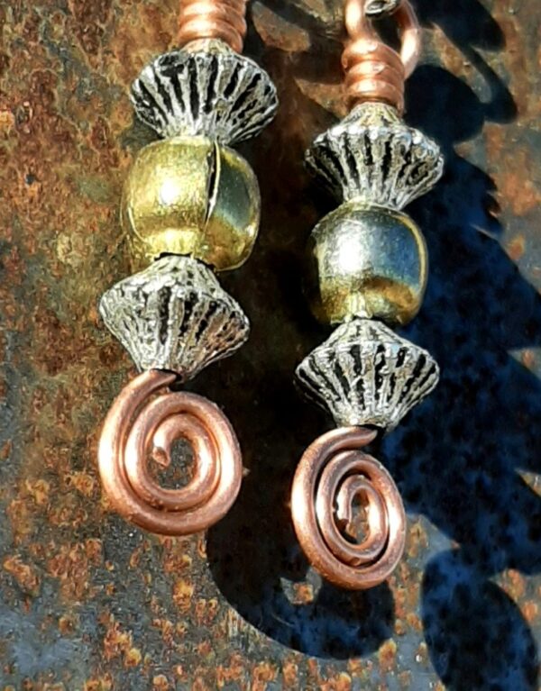 Each earring has a round brass bead between two biconic silver-colored beads, all strung on copper wire that ends at the bottom in a neat spiral.