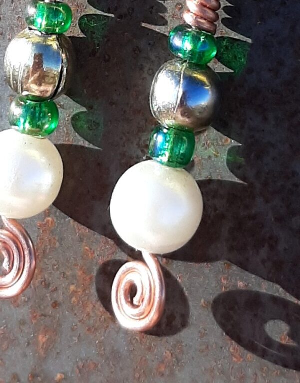 Each earring has, from bottom to top, a round white bead, a kelly green bead, a brass bead, and another kelly green one, all strung on copper wire that ends at the bottom in a neat spiral.