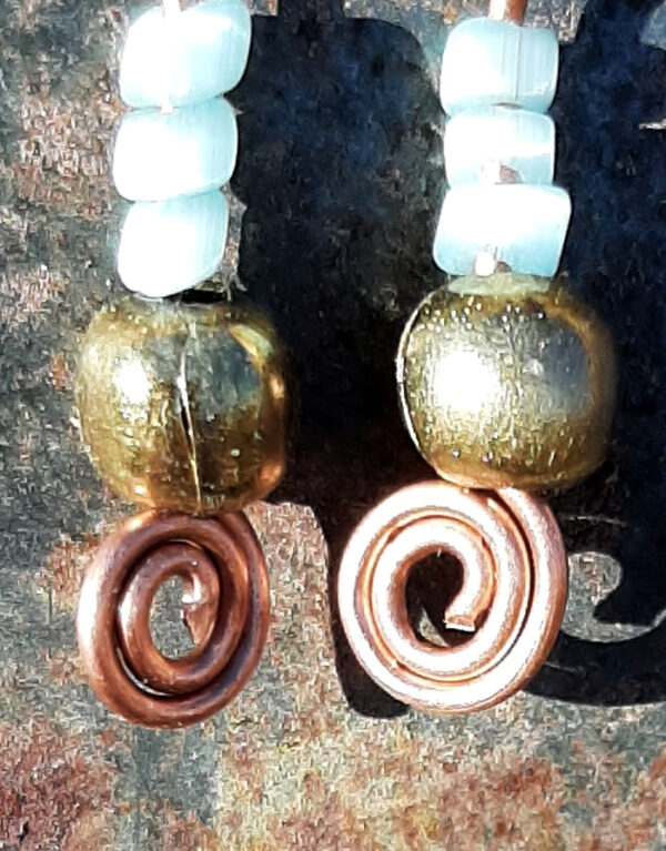 Each earring has a round brass bead with three pale blue beads above it. All are strung on copper wire that ends at the bottom in a neat spiral.