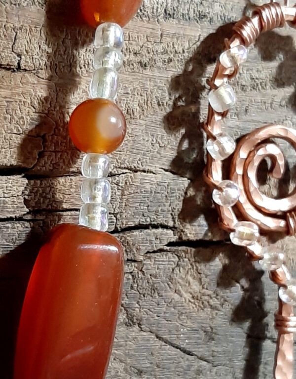 Lovely deep orangey-brown beads set off by lil glass beads that are MOSTLY clear but have just a tint of yellow, plus a pointer & finger loop of hammered copper wire.